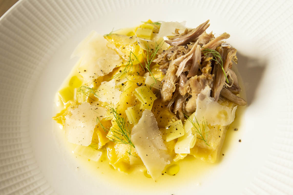 Plated Duck Confit Agnolotti featuring housemade pasta, parsnip and leeks.